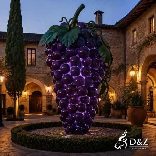 Purple grape sculpture with lights displayed in a winery courtyard at night